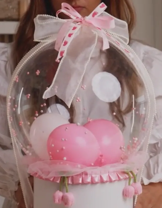 A pink bubble-balloon globe hamper finished with a heart ribbon