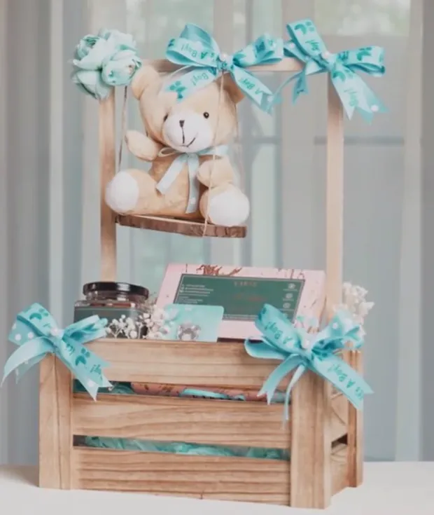 A wooden crate hamper with a teddy on a swing